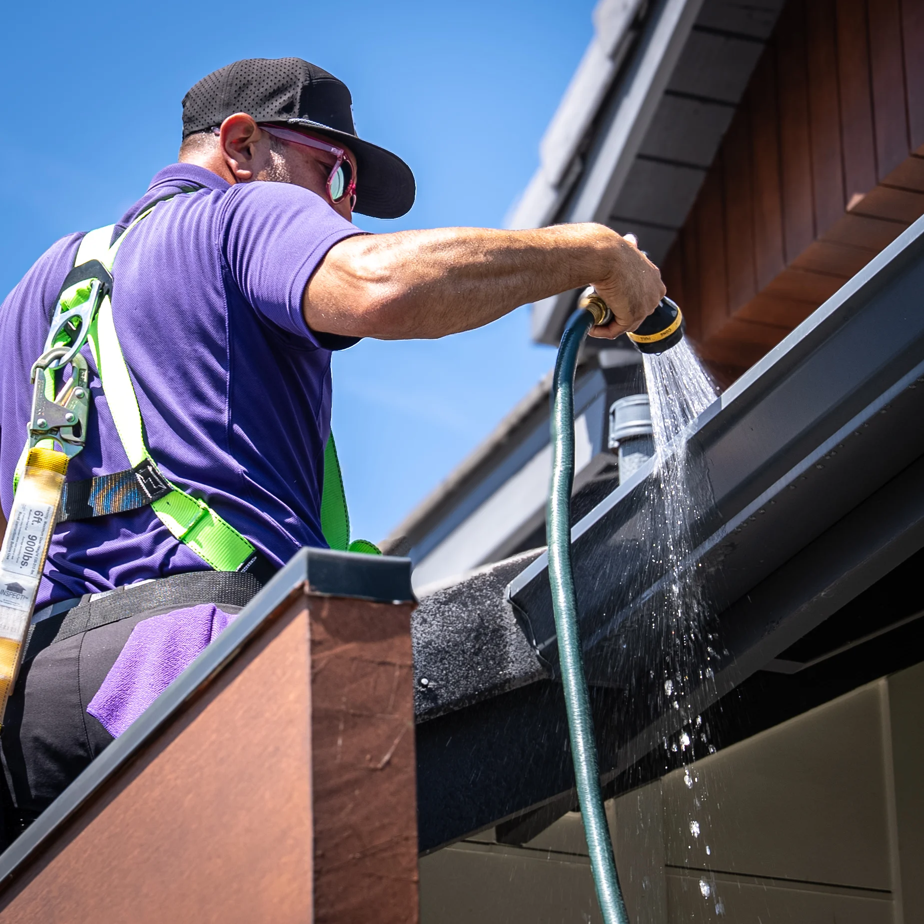 Professional gutter cleaning technician removing leaves and debris from residential gutter system