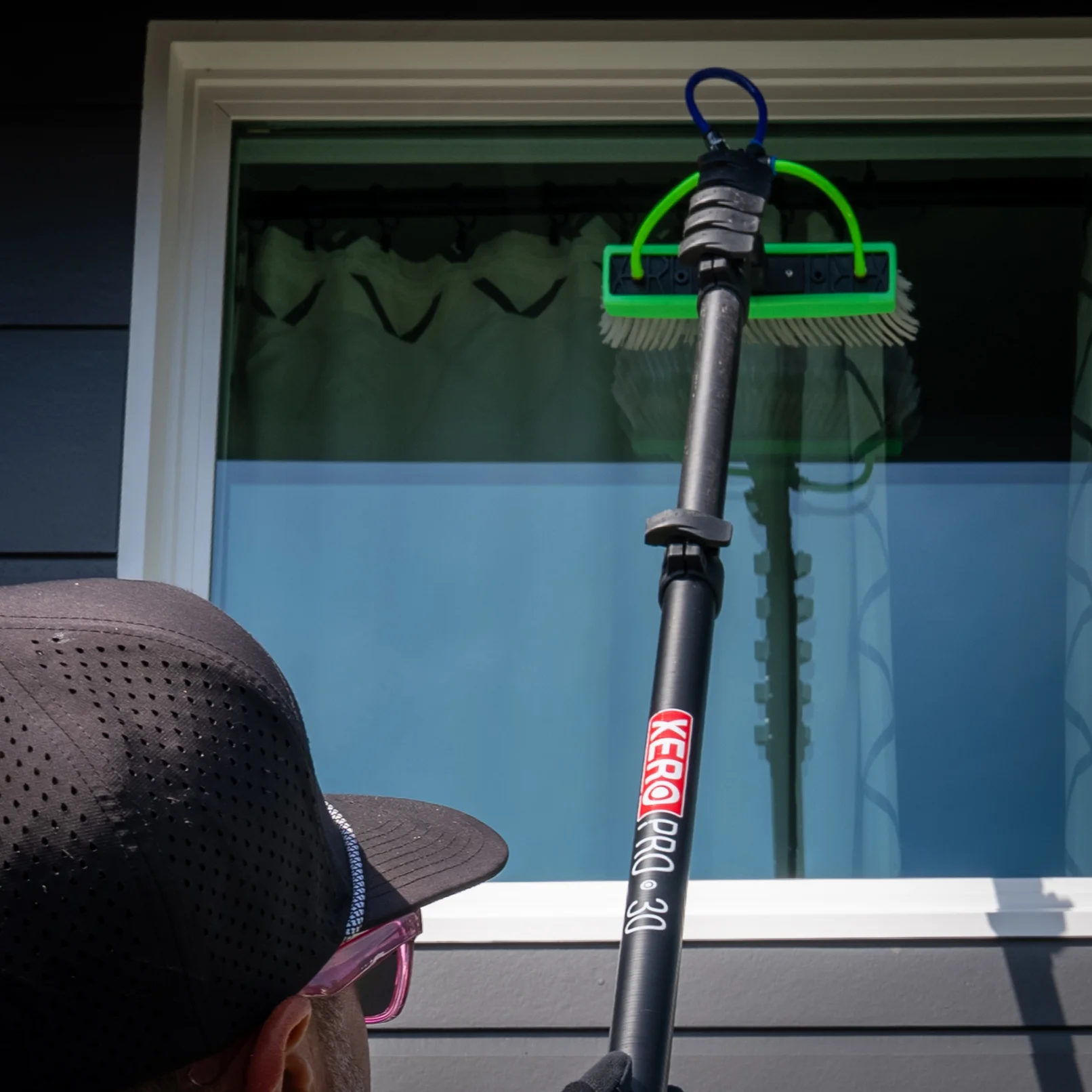 Professional window cleaner using squeegee on residential home windows in San Diego