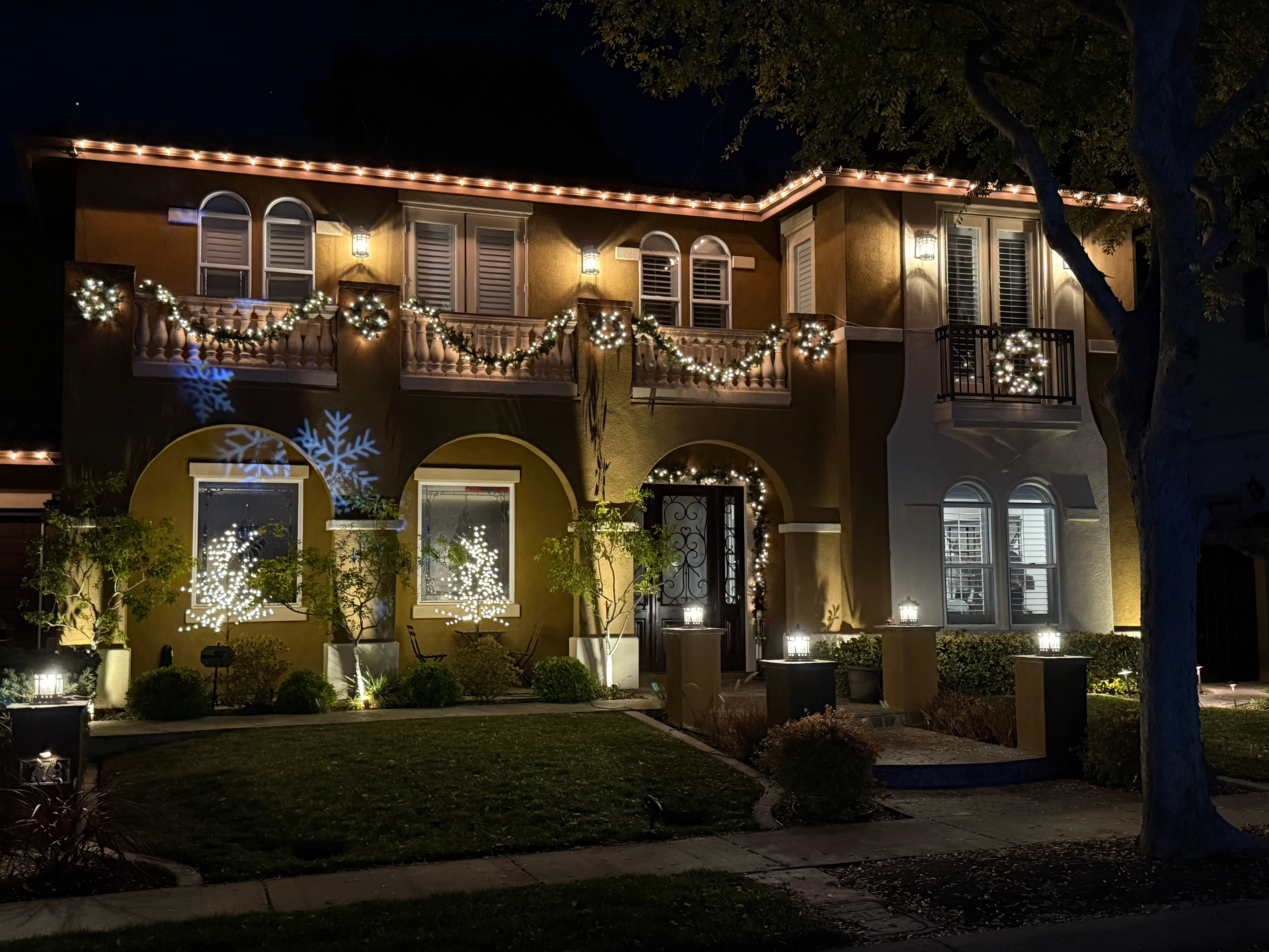 Illuminated two-story home at night with clean windows and holiday garland decorations