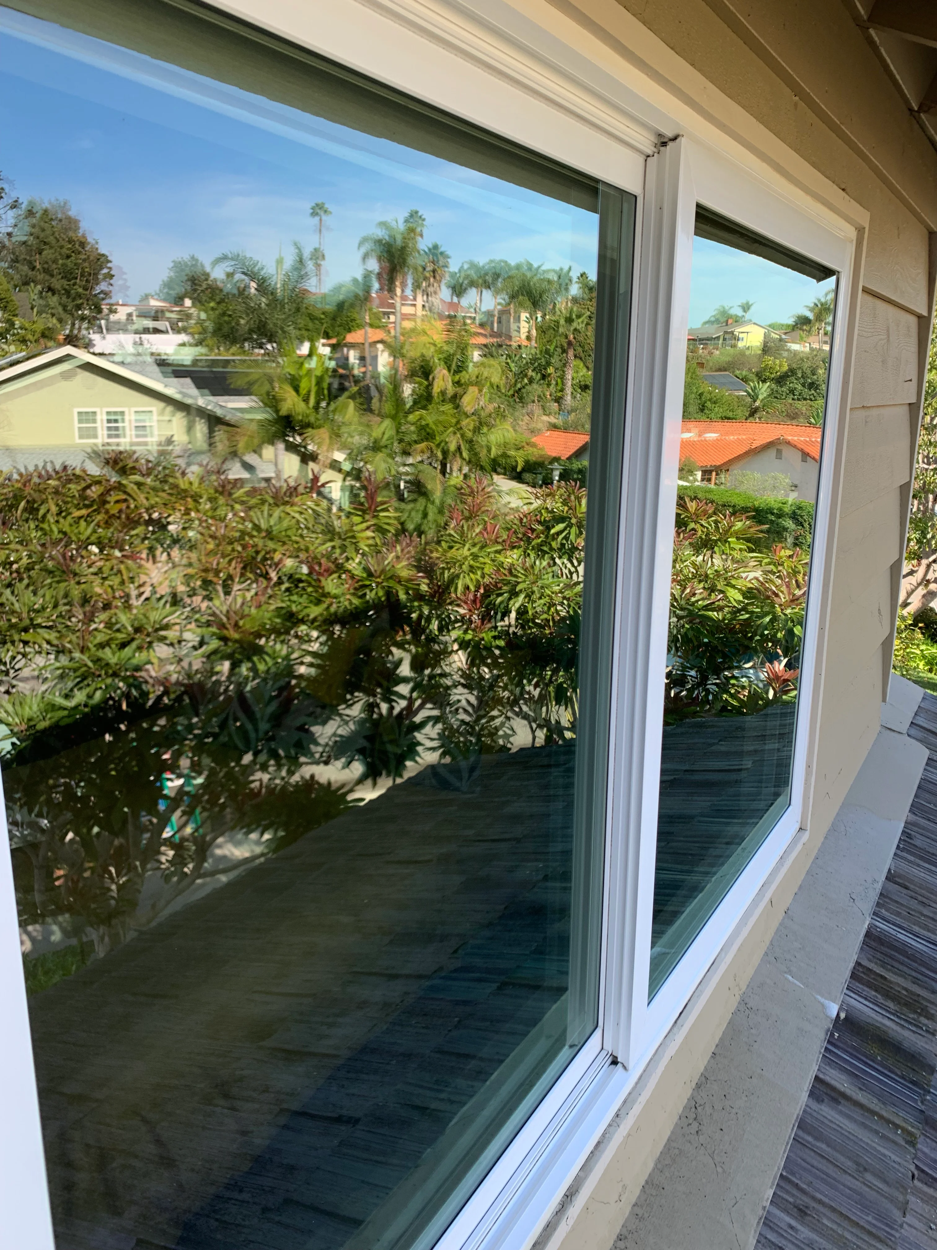 Clean sliding glass doors with white frames overlooking San Diego neighborhood with palm trees